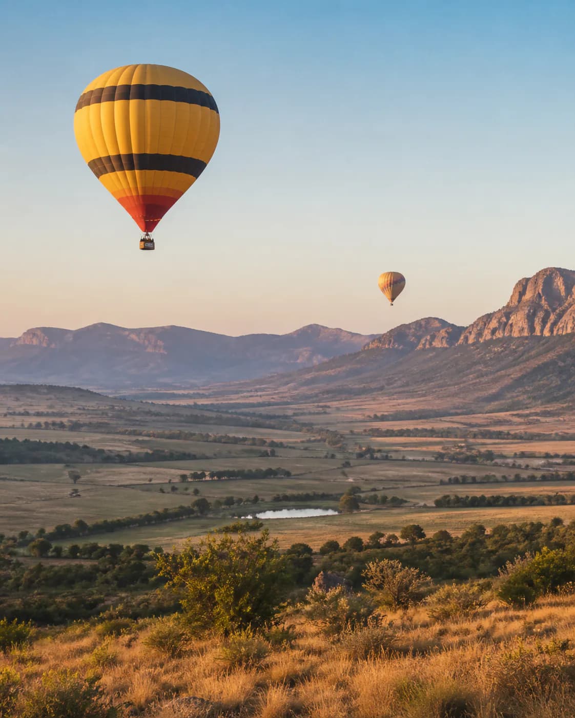 Hot-air balloons floating above a broad mountain valley
